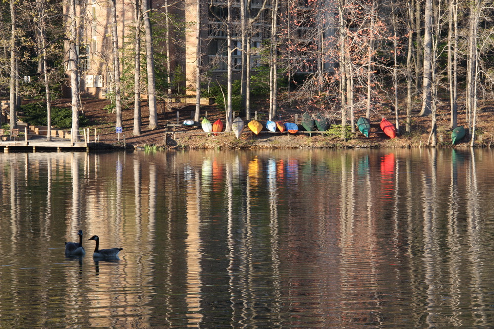 colorful canoes across the lake reflecting on the water 